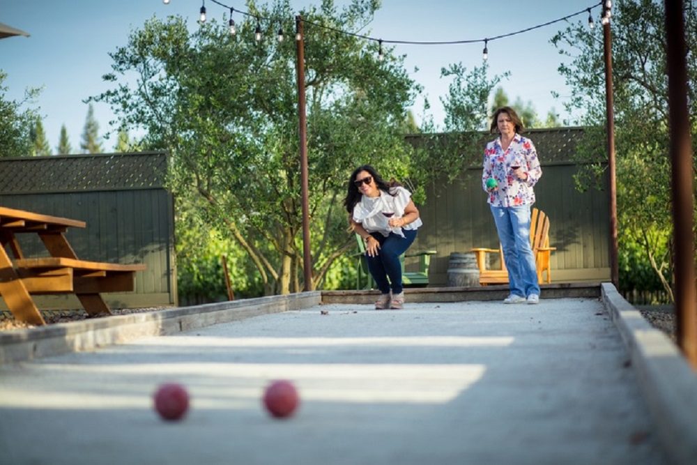 Two Women Drinking Wine and Playing Bocce