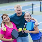 three people laughing in pickleball court