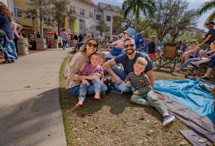 Family of four sit on grass the 2023 Blues, Brews & BBQ Festival