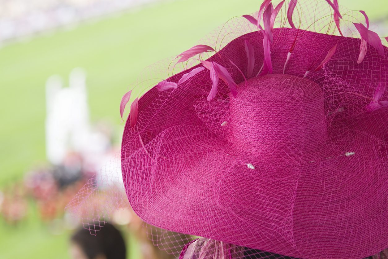 A fashionable stylish, bright pink, straw, netting and feather ladies hat.