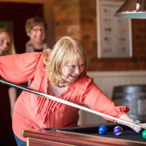 A group of three middle aged women playing pool.