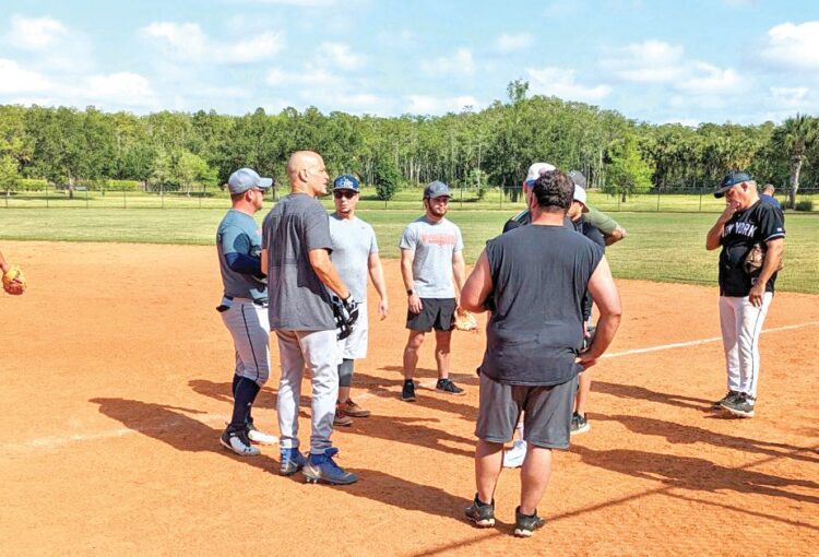 Group of people gathering on a softball field