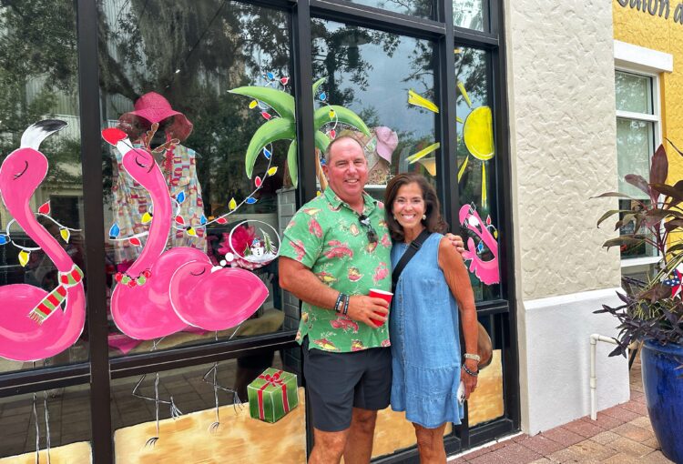 couple posing in front of a flamingo painted window