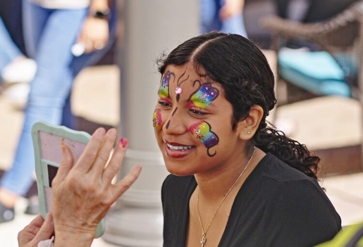 Girl gets butterfly design painted on her face at 2024 Taste of Ave