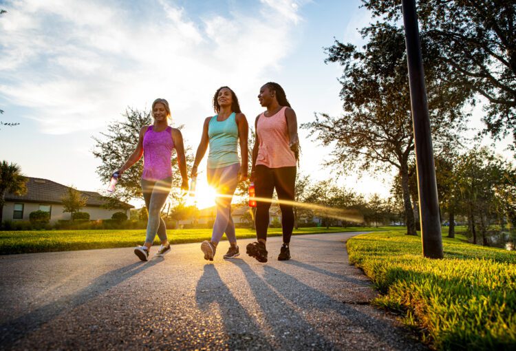 Group of three adult friends enjoy a morning walk around Ave Maria lake