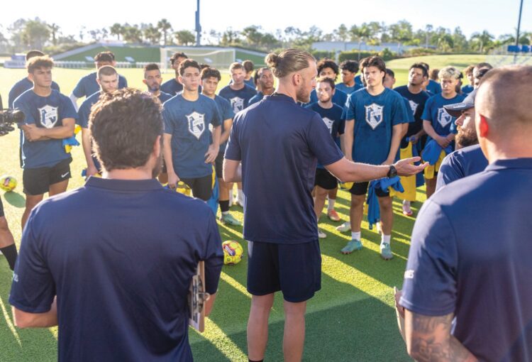 Coach Matt Poland and the FC Naples team discussing a game plan for the upcoming match. 